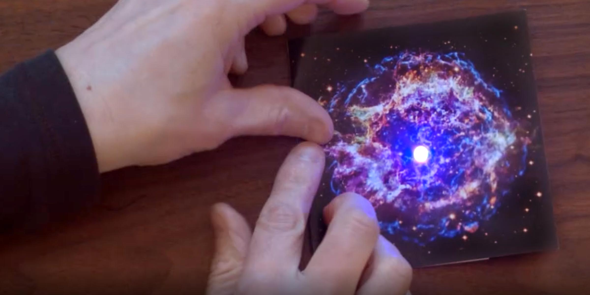 Hands folding a Paper with an astronomical image on it