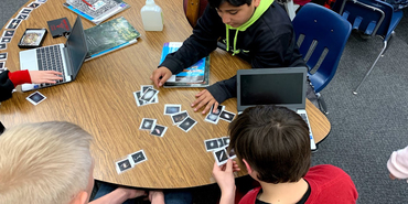 Children at a table with books, laptops and astronomical cards